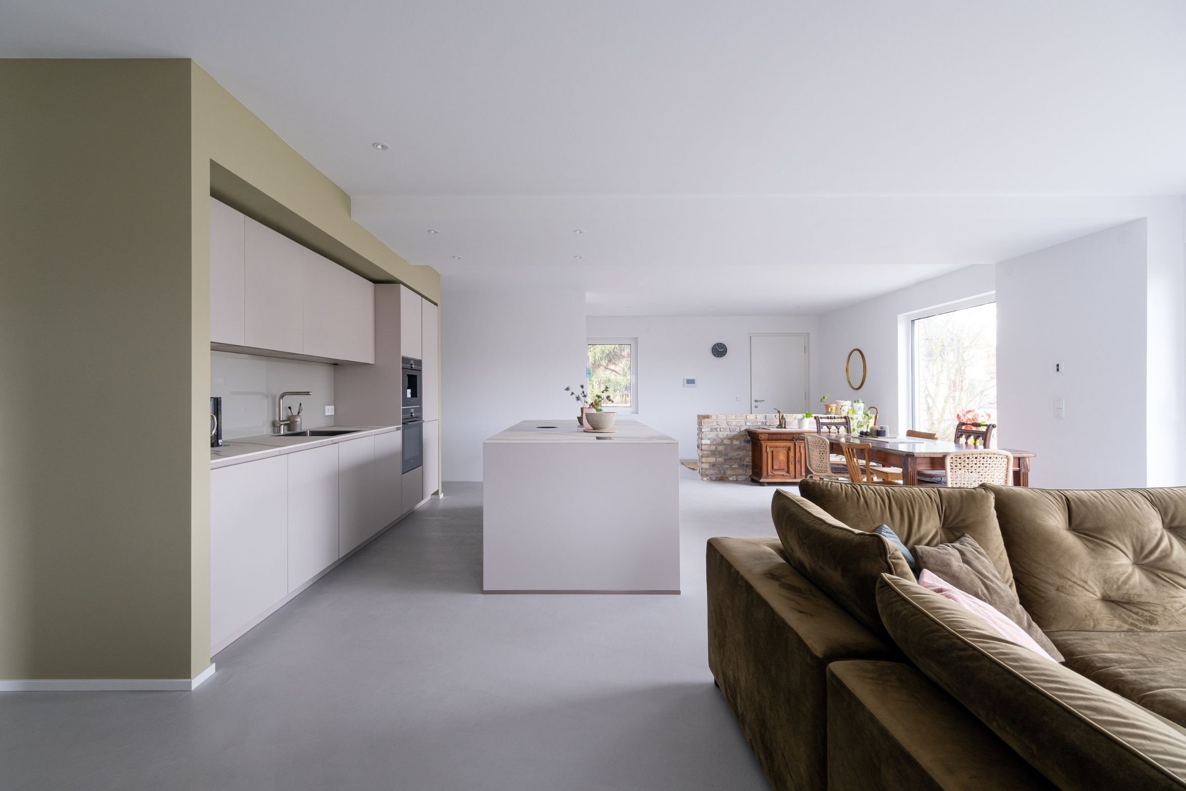 Appartement R, offener Wohnbereich mit Küche, Kochinsel und braunem Samtsofa