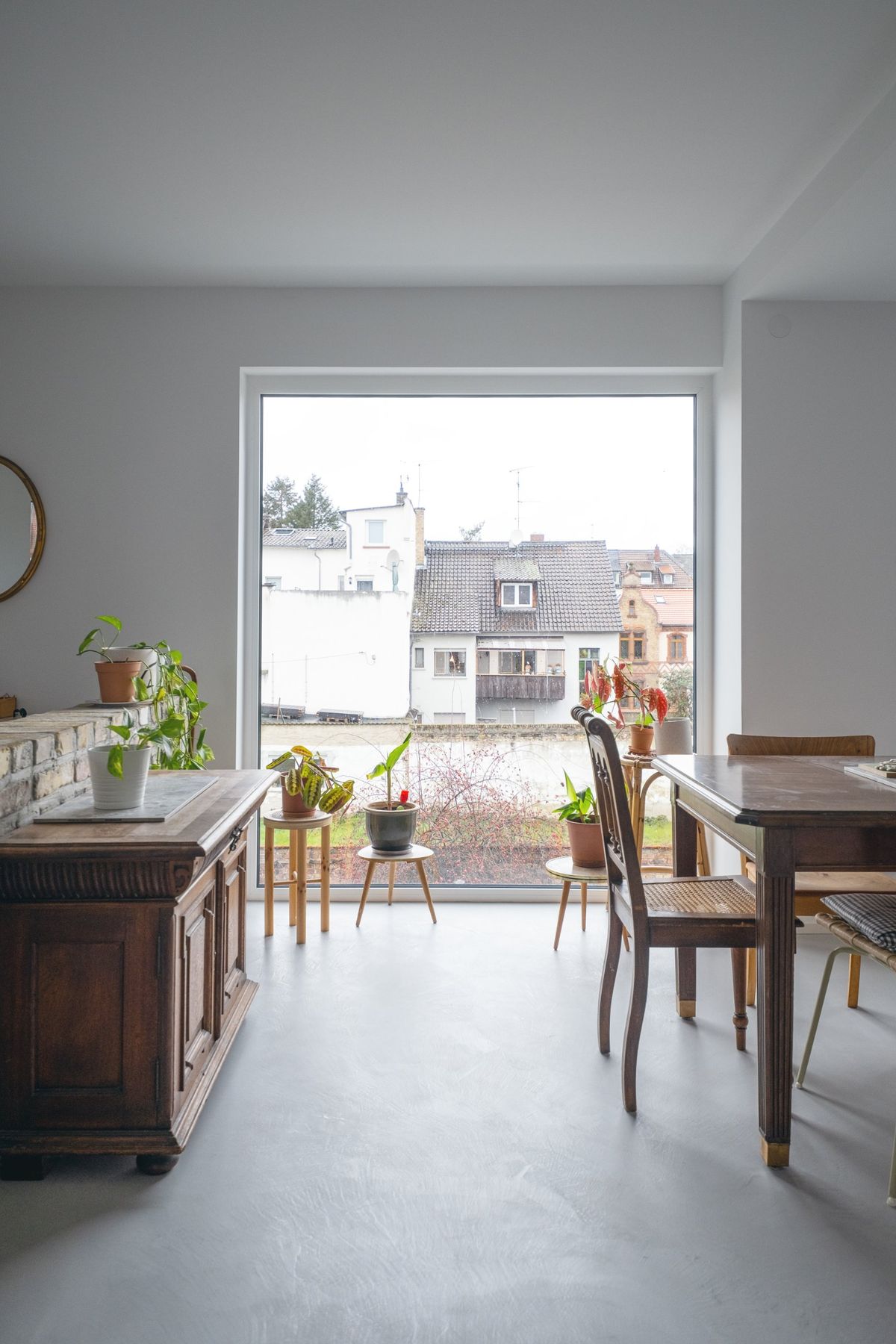Appartement R, Esstisch und Holzkommode vor bodentiefem Fenster