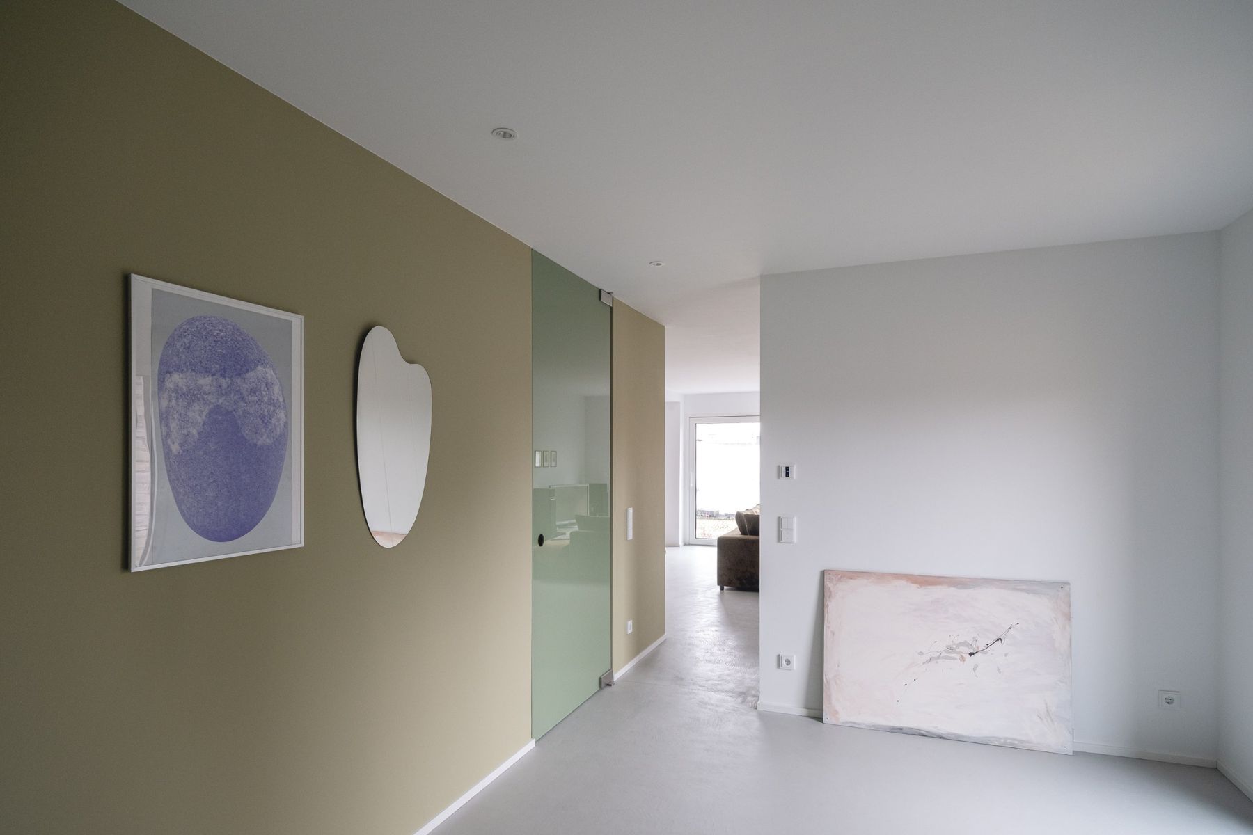 Appartement R, Flur mit olivgrüner Wand, Kunstwerken und Glasschiebetür