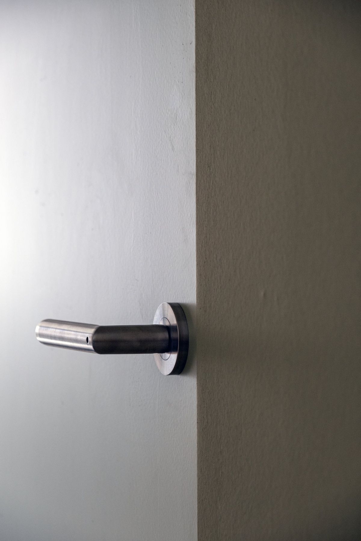 Appartement R, Edelstahl-Türgriff an einer Holztür