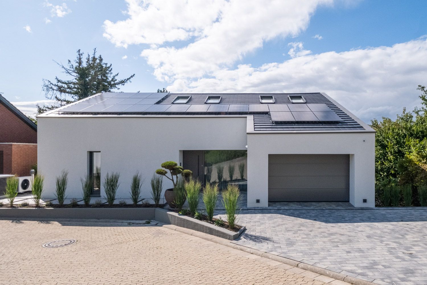 Haus K in Gau-Algesheim: Straßenansicht mit Solardach, Garage und Zierbäumen