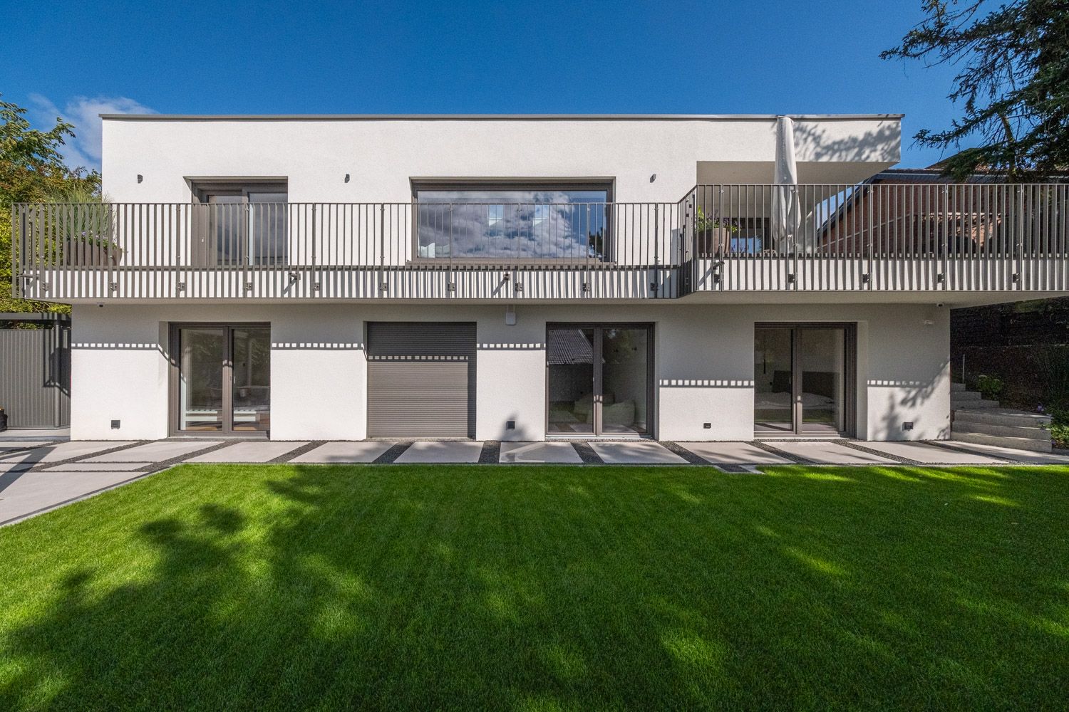 Haus K, Gartenfassade mit Balkon und Fenstertüren am Rasen