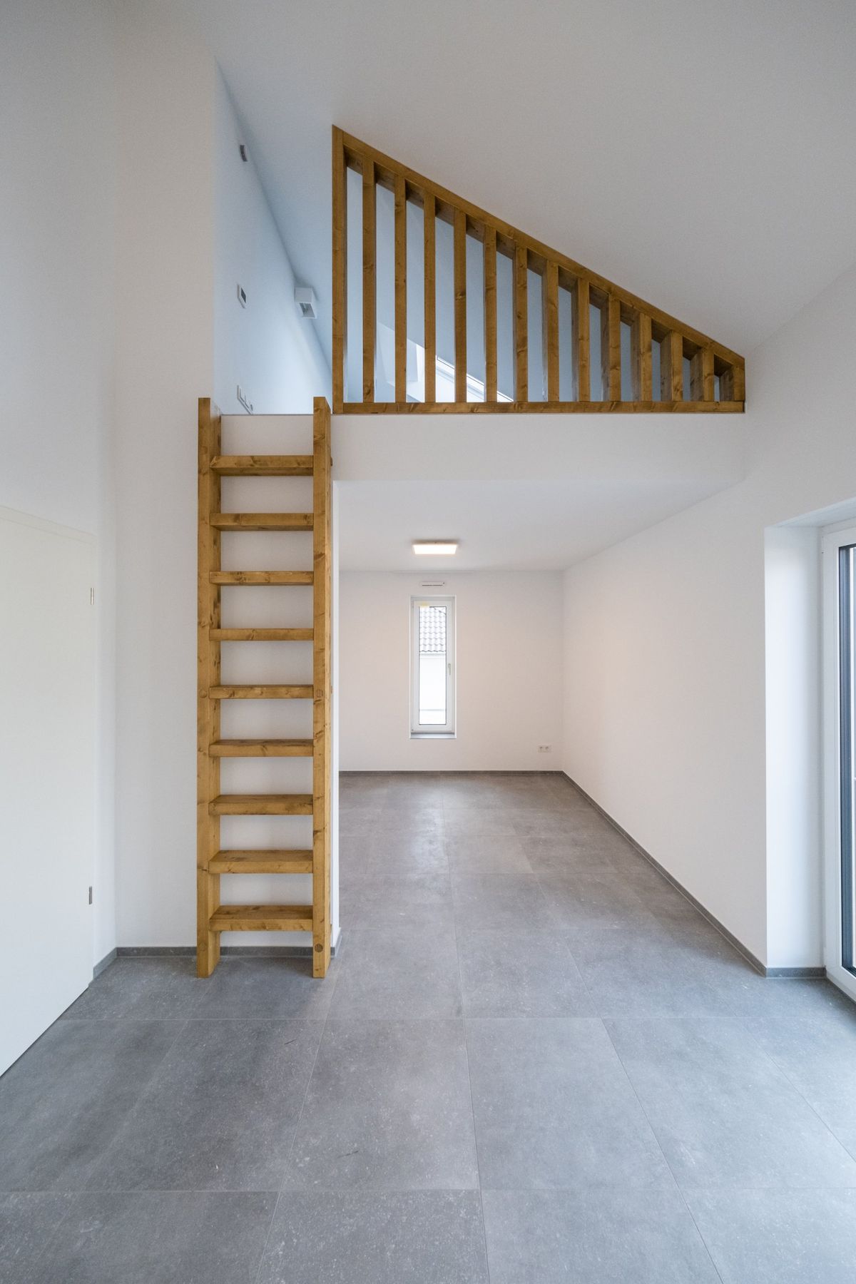 Haus M, leerer Raum mit Leiter zur Galerie und Betonboden