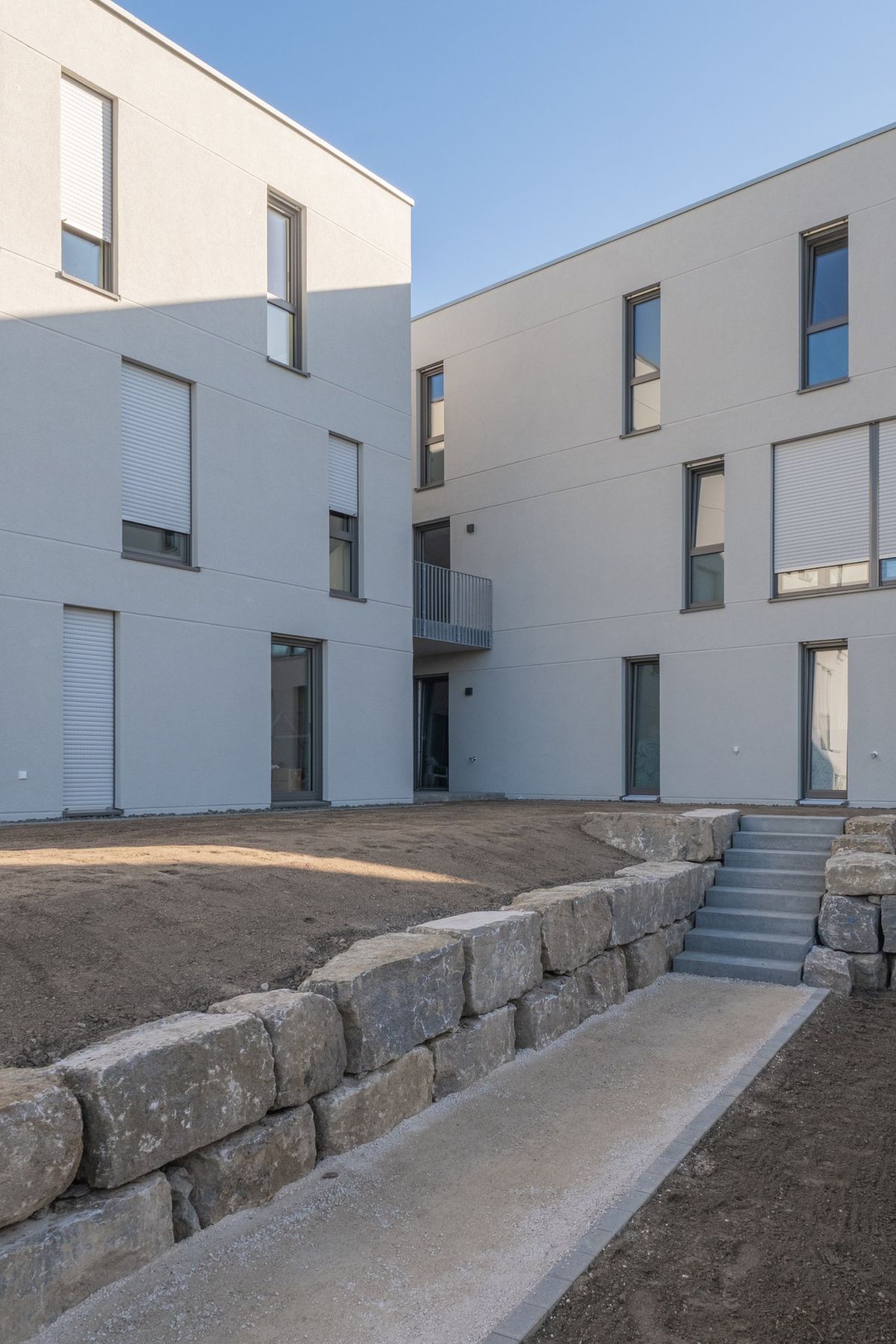 Mehrfamilienhaus K, Natursteinmauer mit Treppe im Hof