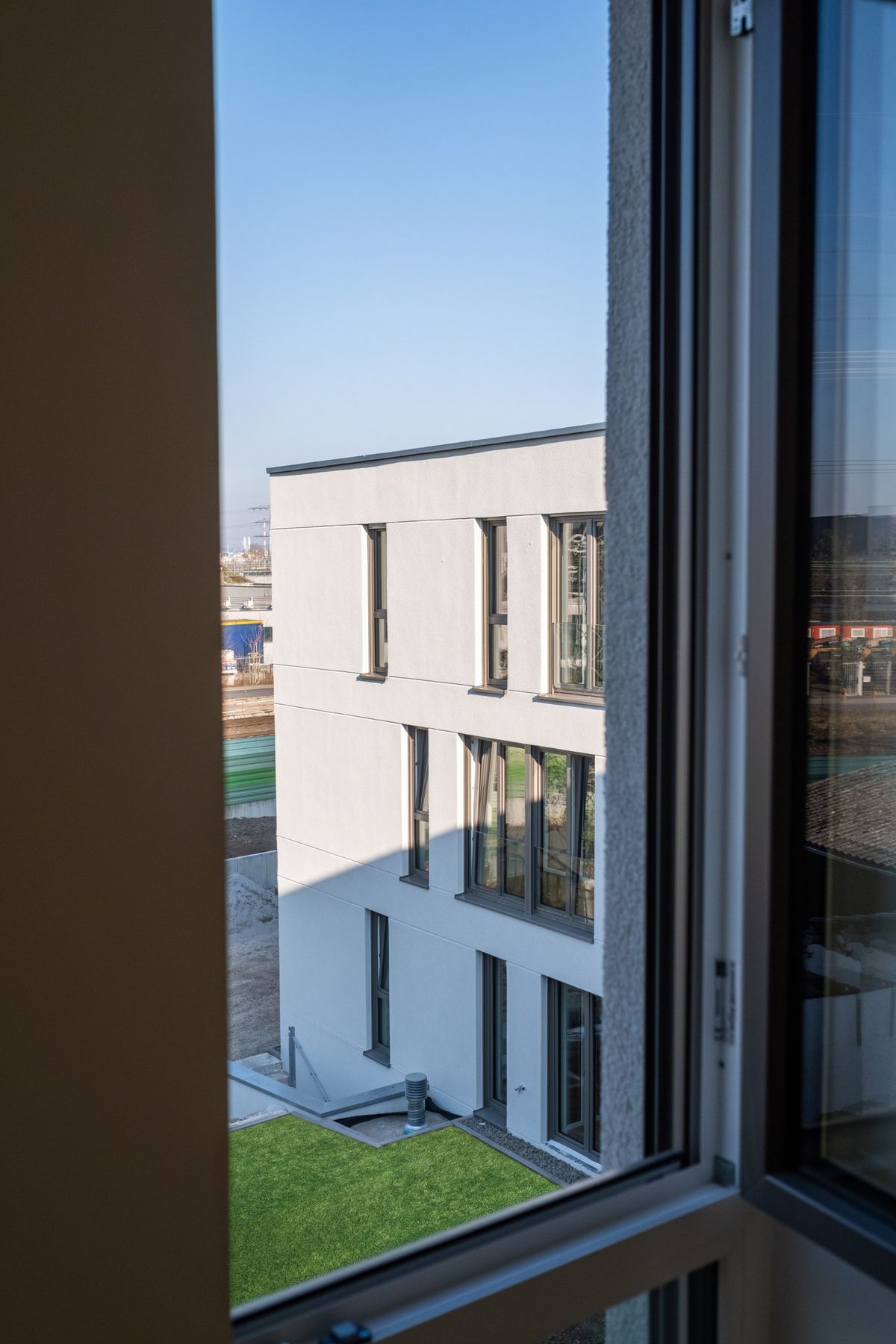 Mehrfamilienhaus K, Blick aus dem Fenster auf den benachbarten Baukörper und den Garten